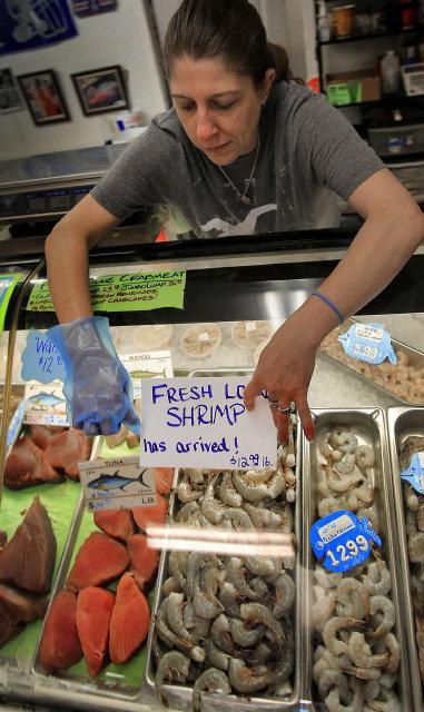 <p>Employee Bert Elliott tapes a "Fresh local shrimp" sign to the glass display case at Murrells Inlet Seafood on Wednesday May 29, 2013 after arrival of shrimp from McClellanville.</p>